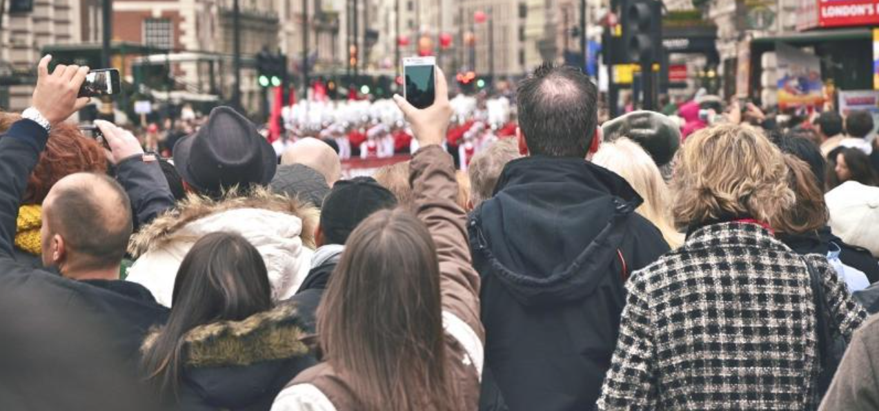 A crowd at a street festival, using their phones. Geo-fencing is a great way to reach your target audience at the right moment on their mobile devices.