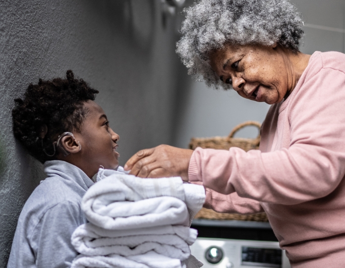 african-american-boy-with-hearing-aid-and-grandmother-doing-laundry