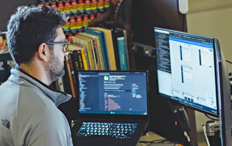 A man looking at a computer screen with code on it, alluding the development of types of AI.